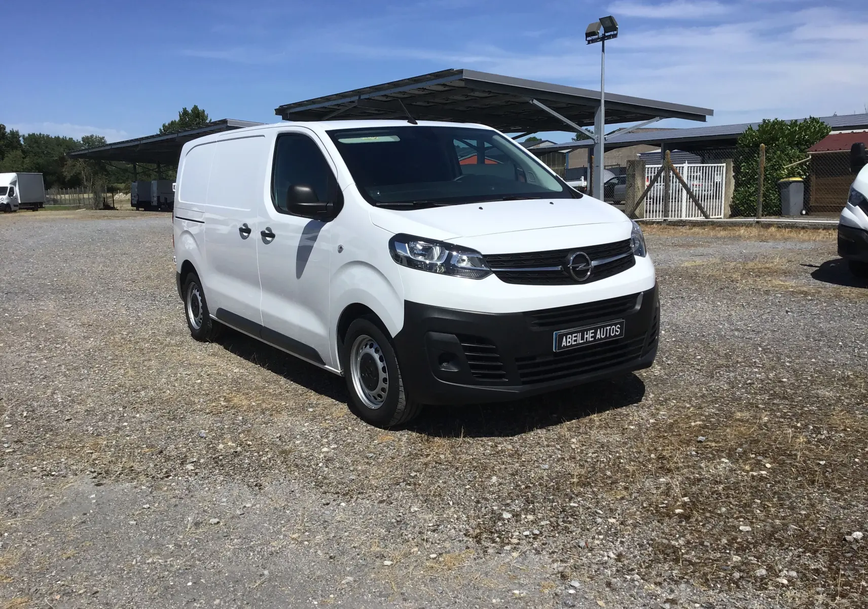 Vue 3/4 avant gauche d'un utilitaire Opel Vivaro blanc 2023 avec pare-chocs noir et jantes tôles simples.
