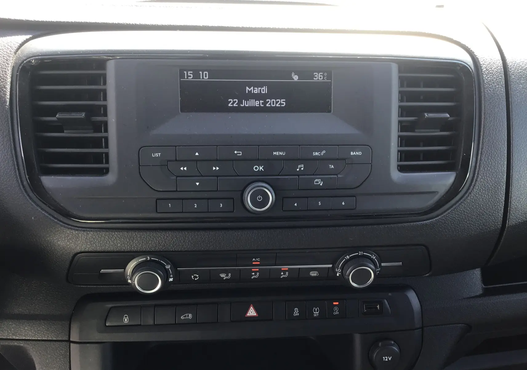 Tableau de bord central de l'Opel Vivaro blanc 2023, avec écran multifonction et commandes de climatisation visibles.