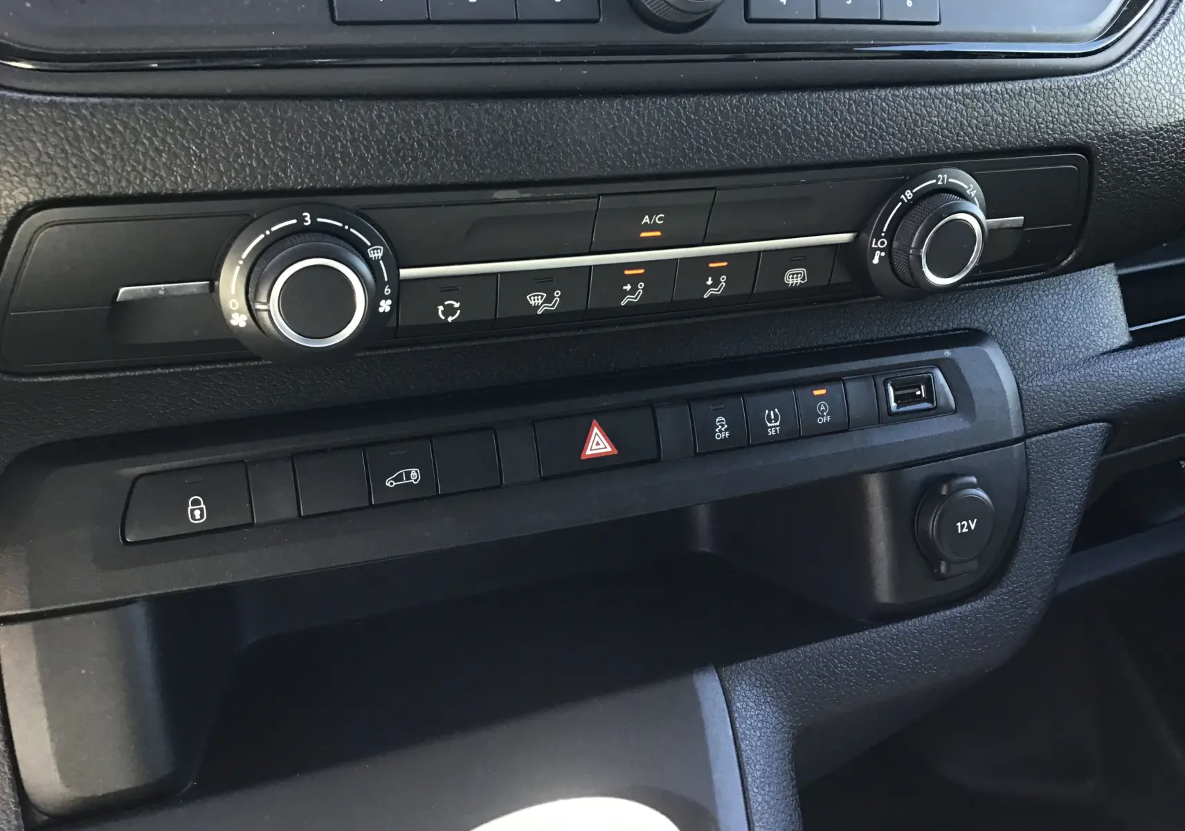 Vue rapprochée du tableau de bord noir de l'Opel Vivaro blanc 2023, mettant en valeur les commandes de climatisation et boutons fonctionnels.