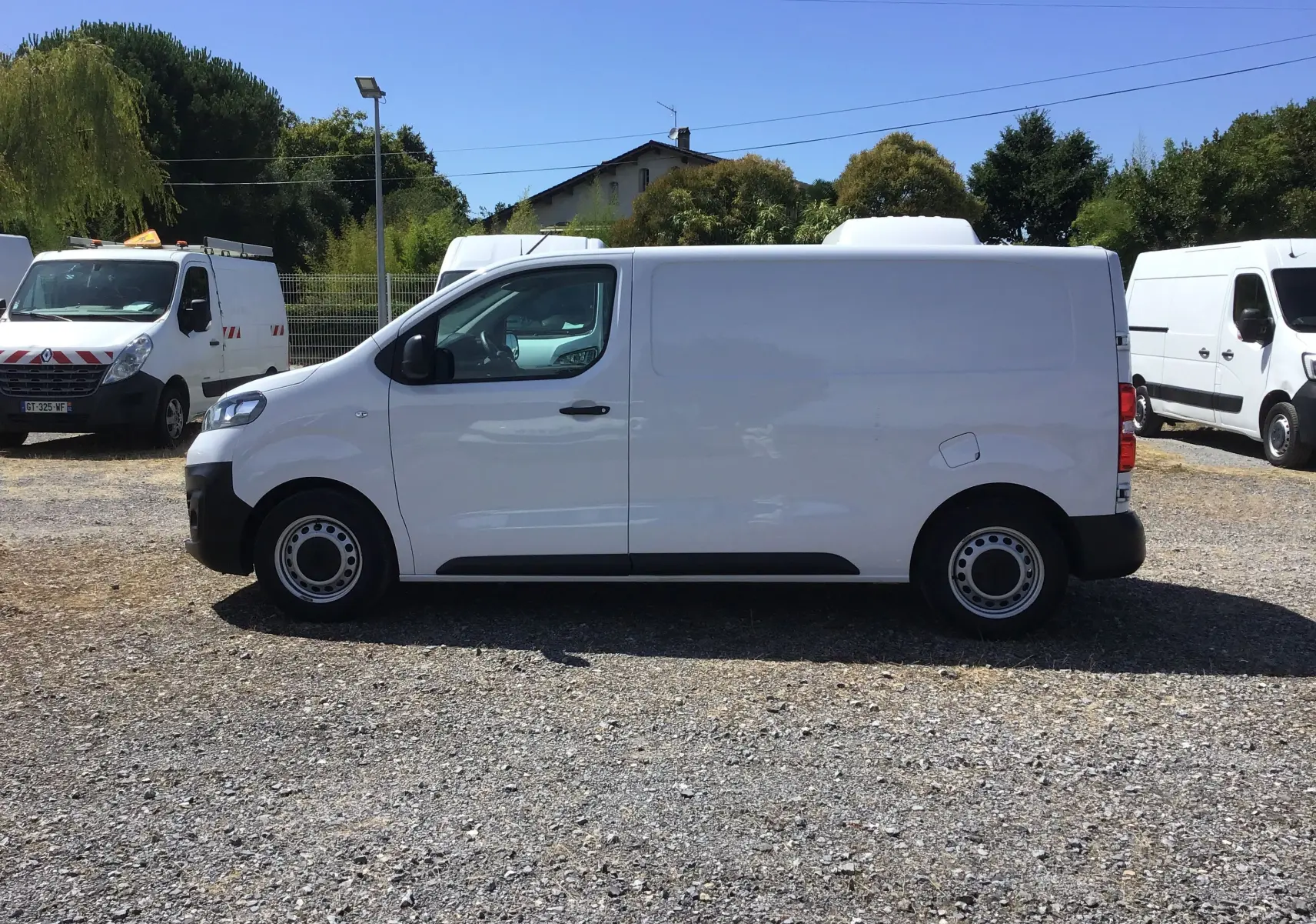 Profil côté gauche d'un utilitaire blanc Opel Vivaro 2023, version M 1.5 BlueHDi 120, sur un parking extérieur.