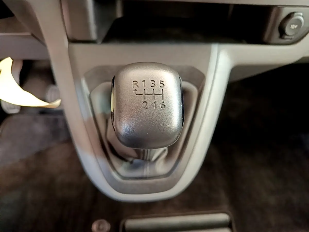 Gros plan sur le levier de vitesses manuel noir du Toyota Proace Verso gris clair, avec indication des 6 rapports et marche arrière.