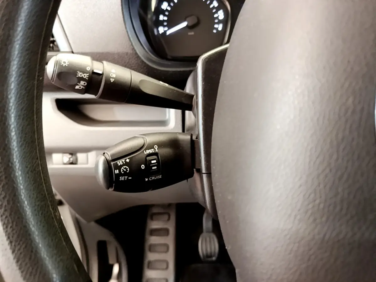 Gros plan sur les commandes de régulateur de vitesse et des phares derrière le volant du Toyota Proace Verso gris clair 2019.