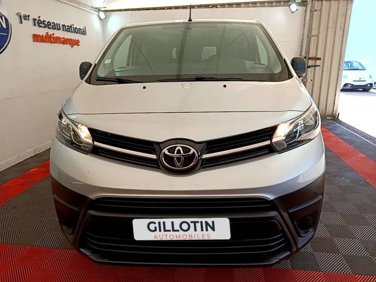 Vue frontale d'un Toyota Proace Verso gris clair avec phares allumés dans un showroom fermé