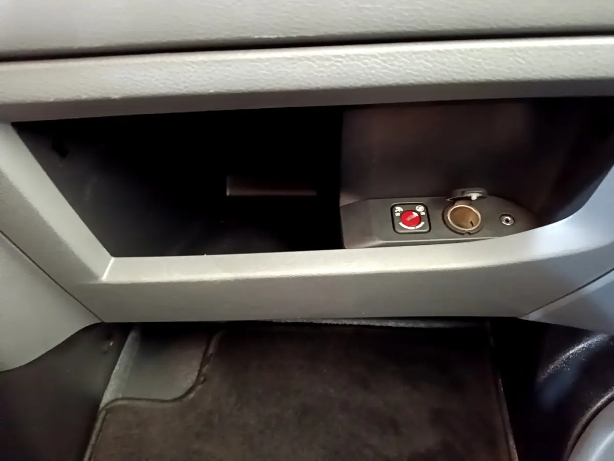 Gros plan sur la boîte à gants grise du Toyota Proace Verso 2019 avec prise 12V et commande rouge intégrée.