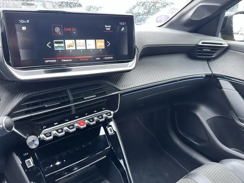 Vue intérieure côté passager du tableau de bord noir de la Peugeot 208 1.2 PureTech 130 GT avec écran tactile et commandes piano.