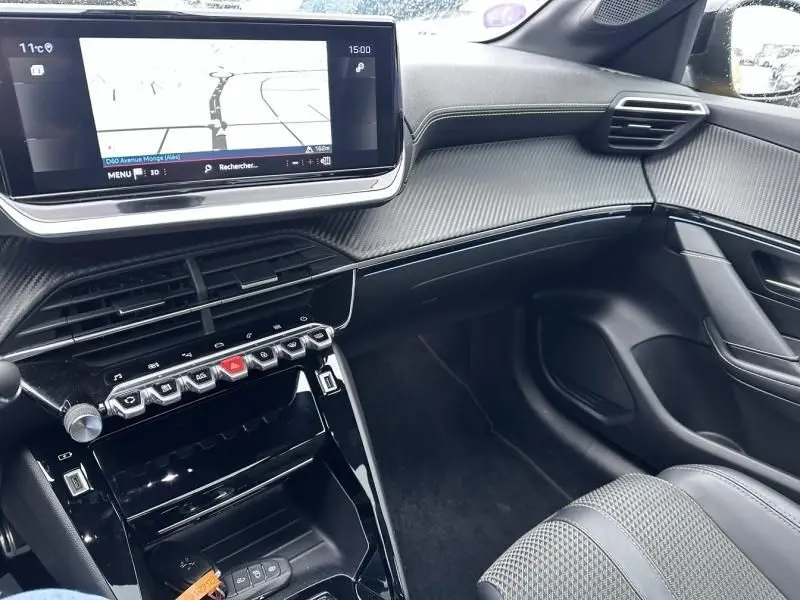 Vue intérieure côté passager de la Peugeot 208 jaune 1.2 PureTech 130 GT avec écran tactile et finition carbone.