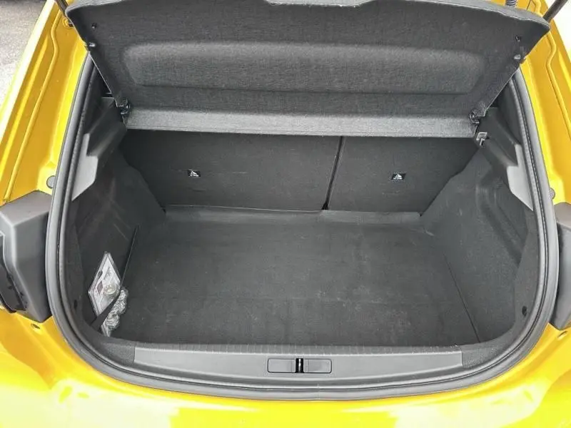 Coffre ouvert vu de dessus d'une Peugeot 208 jaune 1.2 PureTech 130 GT EAT8, montrant l'espace de chargement vide.