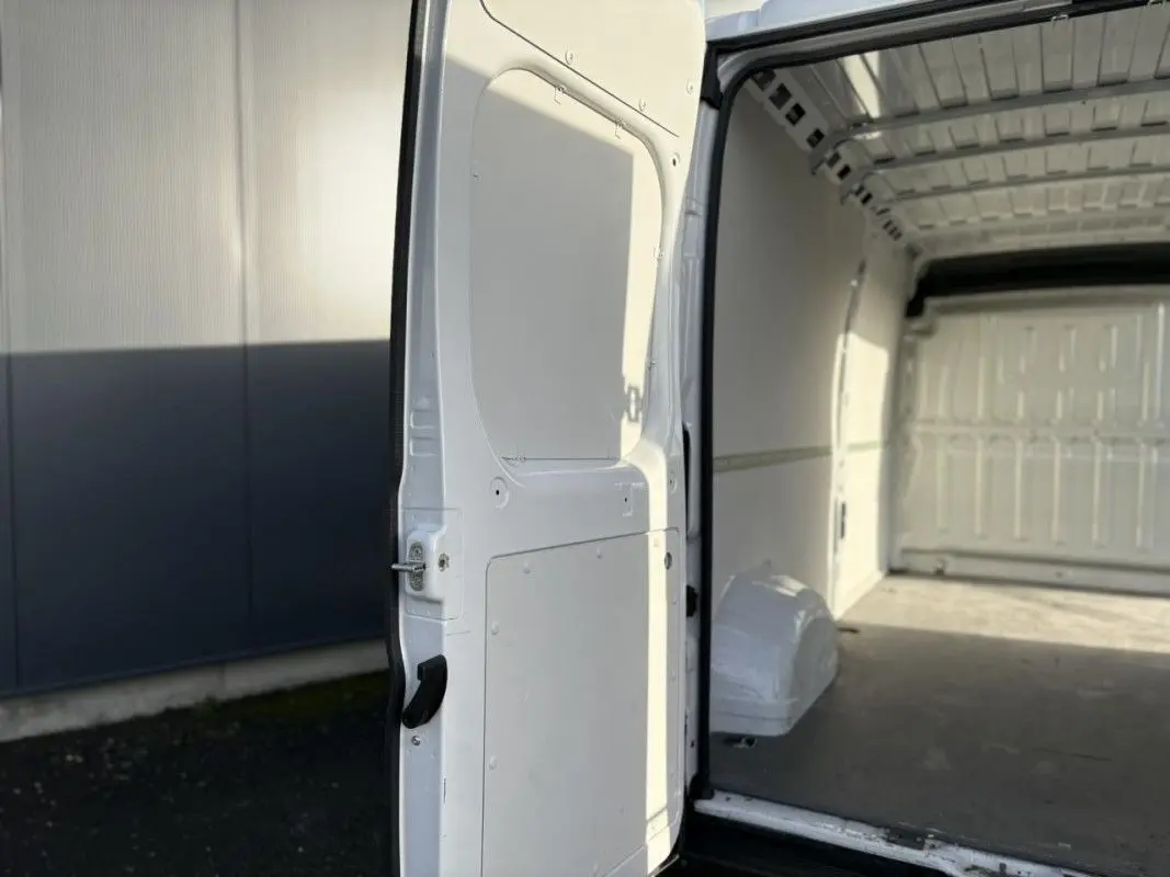 Vue intérieure de la porte latérale ouverte du fourgon blanc Opel Movano 2023, montrant l’espace de chargement vide.