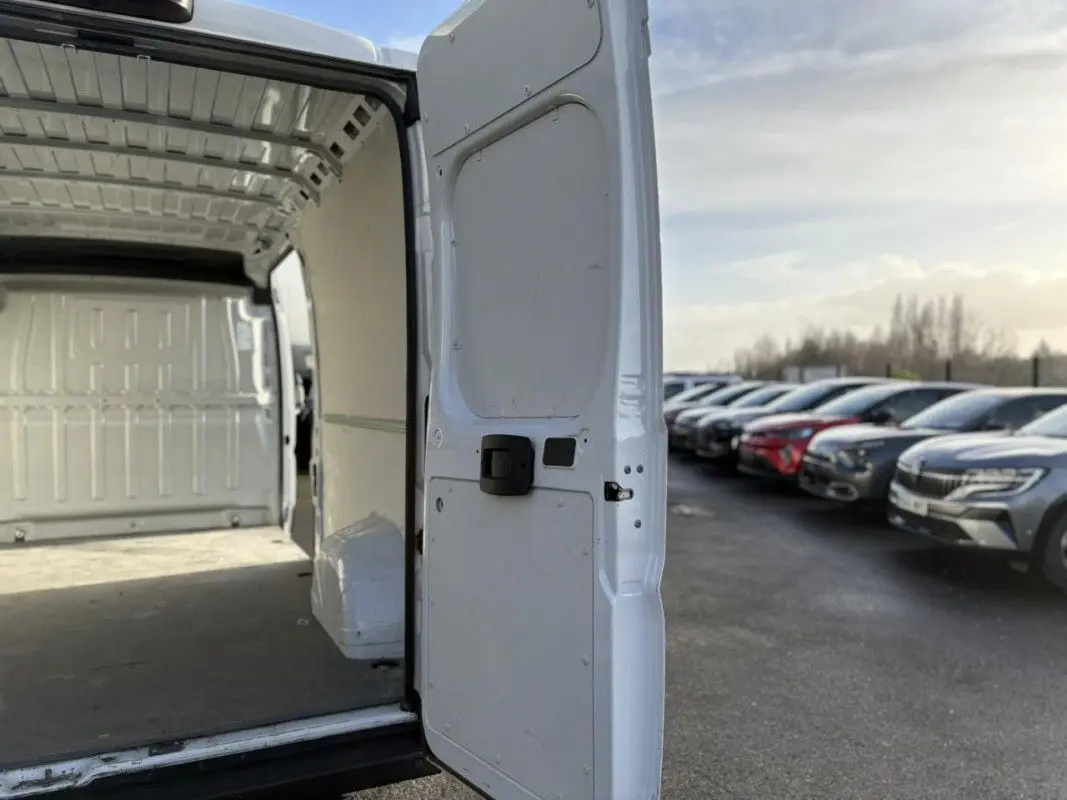 Vue arrière droite du fourgon blanc Opel Movano 2023 avec porte arrière ouverte montrant l’espace de chargement vide.