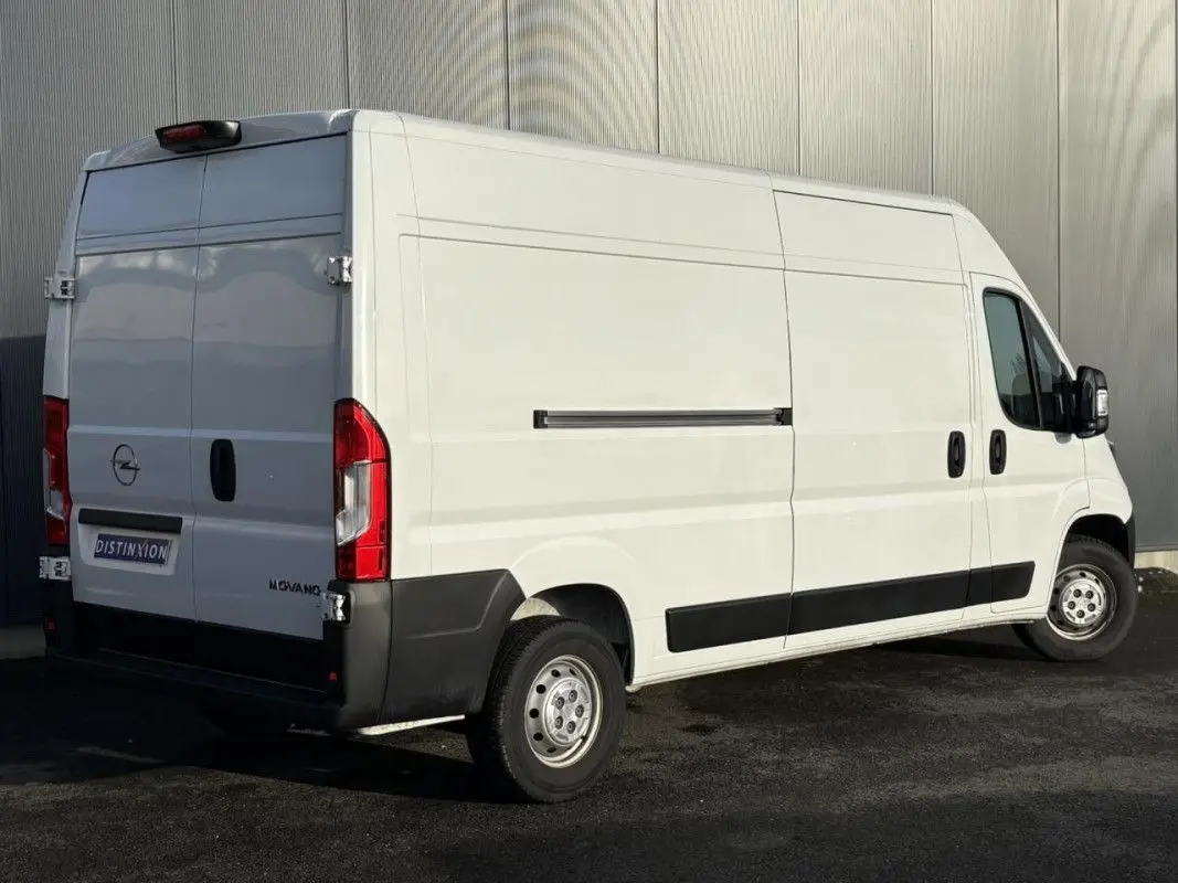 Vue 3/4 arrière droite d’un Opel Movano Fourgon blanc 2023 avec portes arrière battantes et protections noires latérales.
