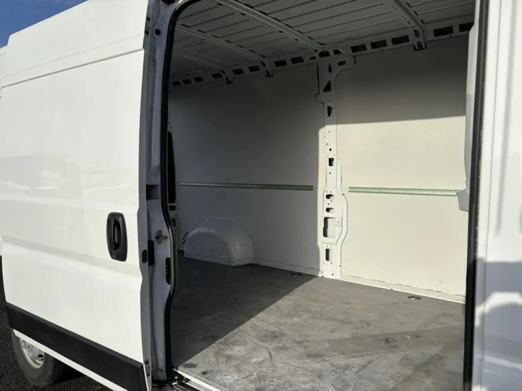 Vue latérale droite du fourgon blanc Opel Movano 2023 avec porte coulissante ouverte montrant l’espace de chargement vide.