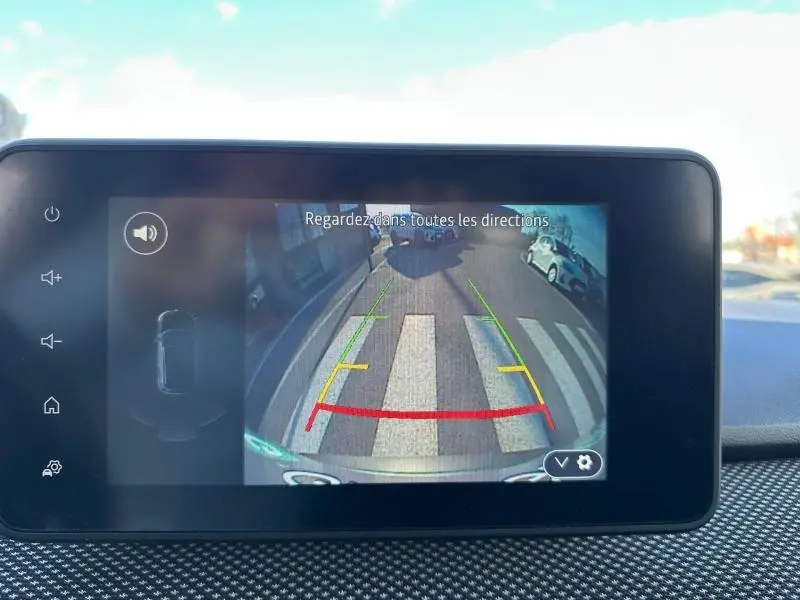Écran tactile intérieur montrant la caméra de recul avec vue arrière sur un passage piéton et véhicules stationnés.