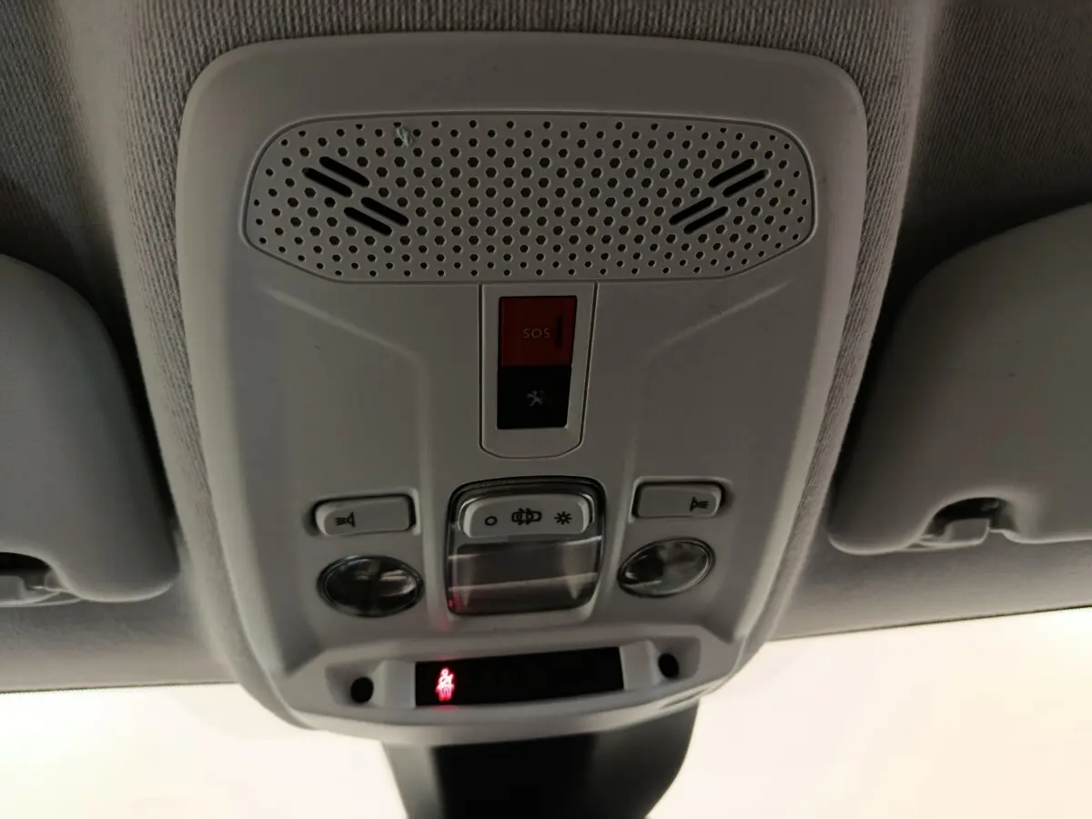 Vue intérieure en gros plan du plafonnier gris avec boutons SOS et éclairage de la Peugeot 208 électrique blanche.