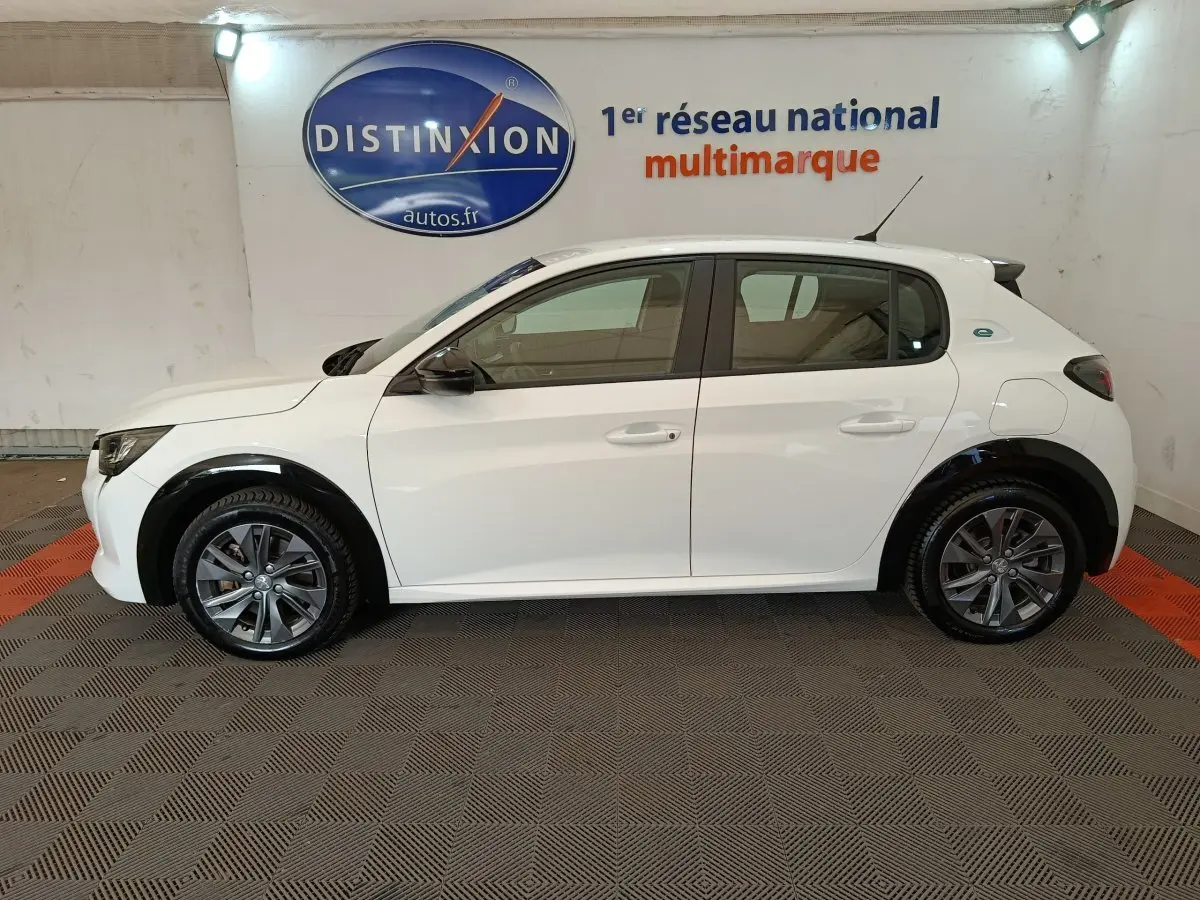 Profil côté gauche d'une Peugeot 208 électrique Active Business R blanche, avec jantes gris foncé et rétroviseurs noirs.