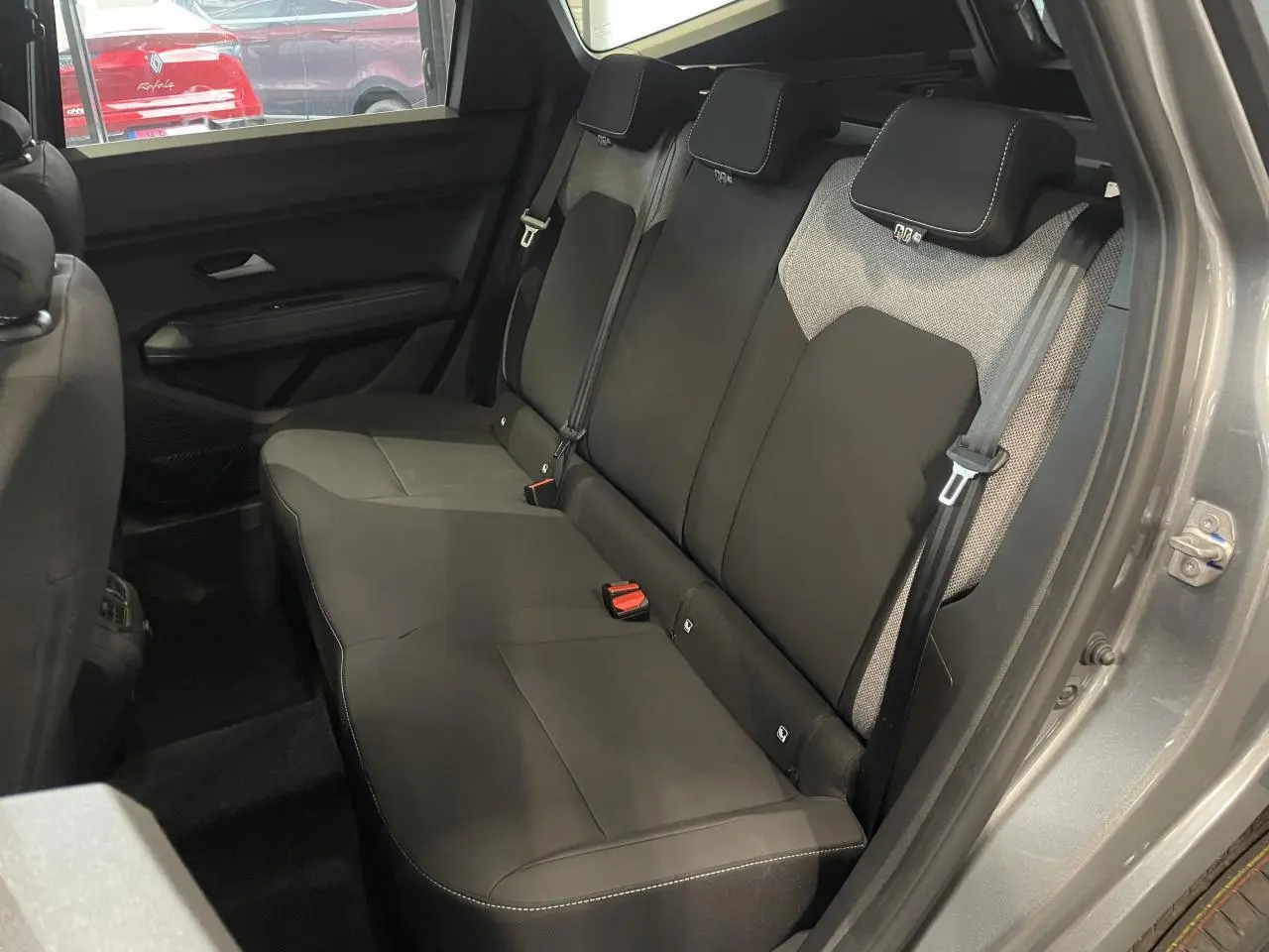 Vue intérieure côté droit sur la banquette arrière gris foncé du Dacia Bigster 2026 avec ceintures et appuie-têtes intégrés.