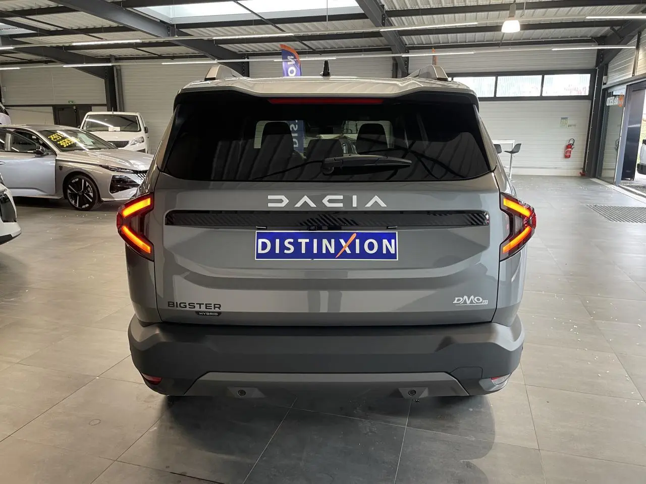 Vue arrière d'un Dacia Bigster gris schiste avec feux LED en forme de C et logo Dacia lumineux.