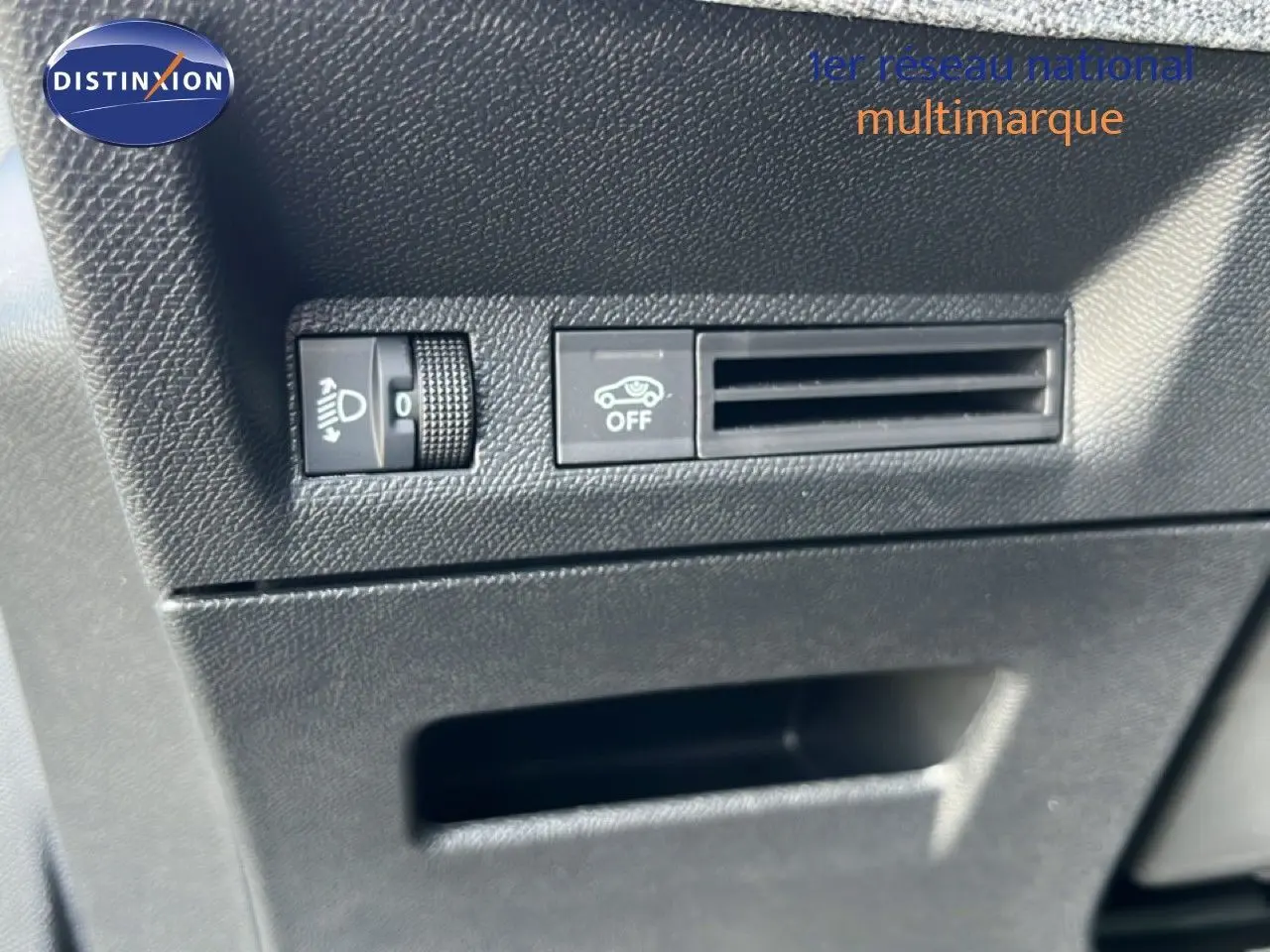 Détail intérieur montrant les commandes de réglage des phares et la ventilation sur un Peugeot 5008 gris Artense 2025.