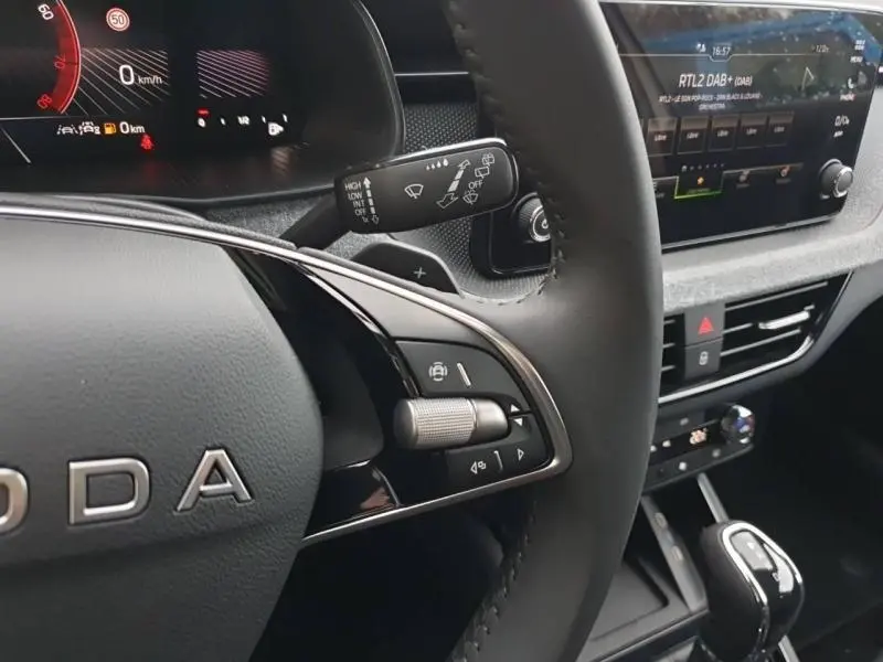 Gros plan sur le volant cuir et la console centrale du Skoda Kamiq gris Diamant, avec écran tactile et commandes au volant.