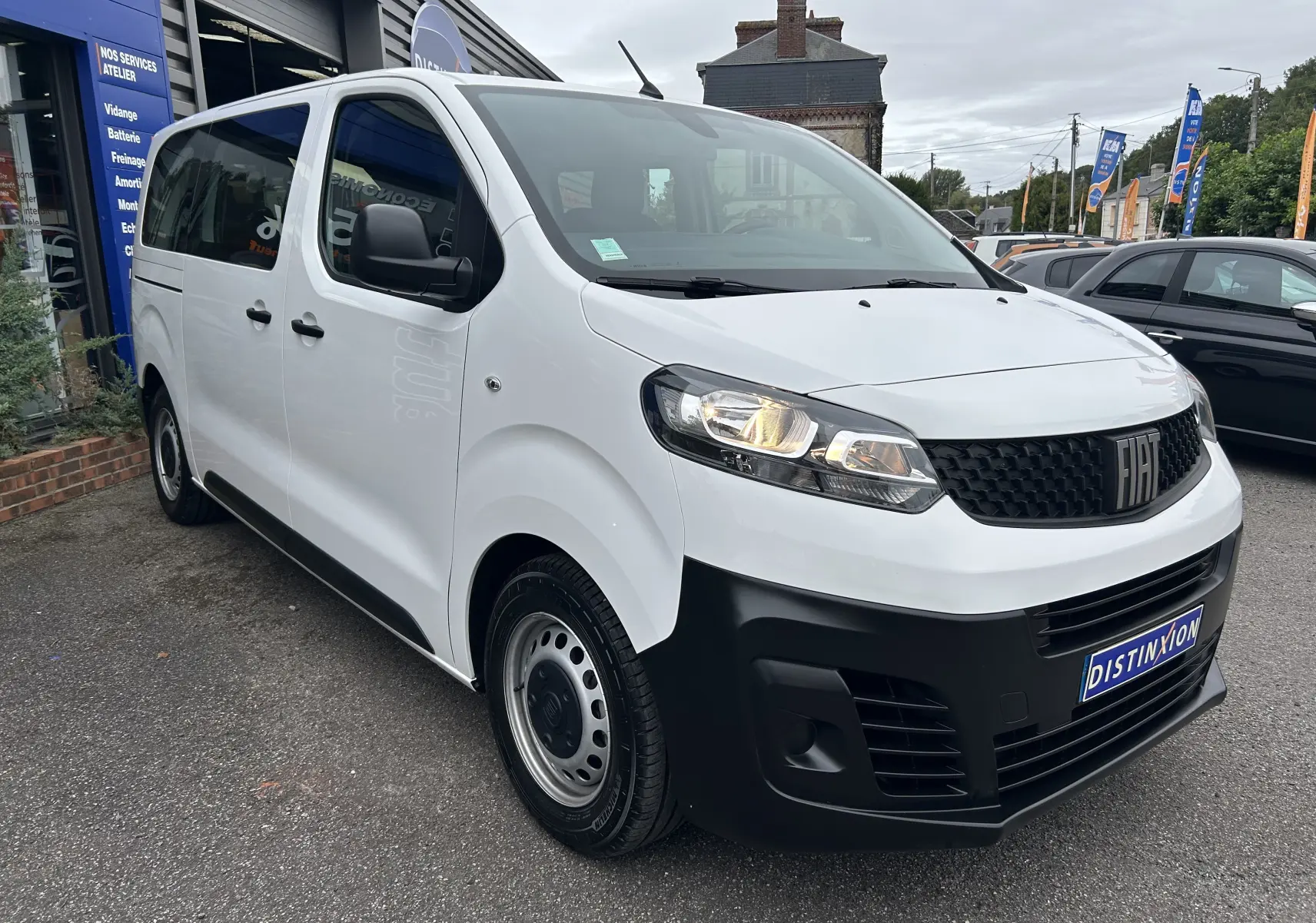 Fiat Scudo Combi électrique blanc vu en 3/4 avant droit, avec calandre noire et phares allumés.