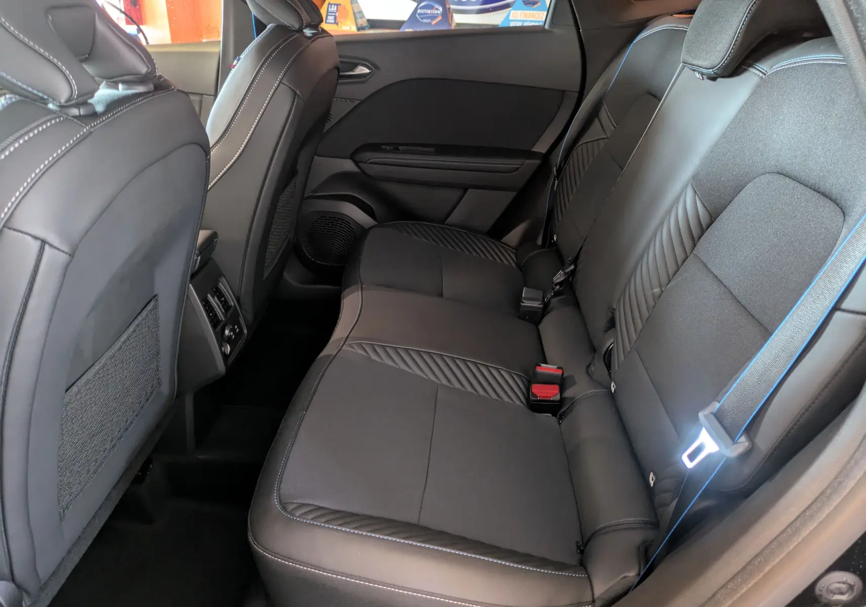 Vue intérieure côté droit sur la banquette arrière noire étoilée du Renault SYMBIOZ E-Tech full hybrid 2025, avec surpiqûres bleues.