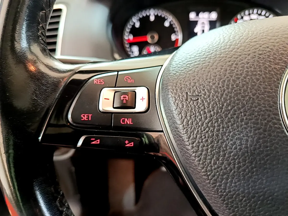 Gros plan sur le volant cuir noir du Volkswagen Sharan 2017, avec commandes de régulateur adaptatif éclairées en rouge.