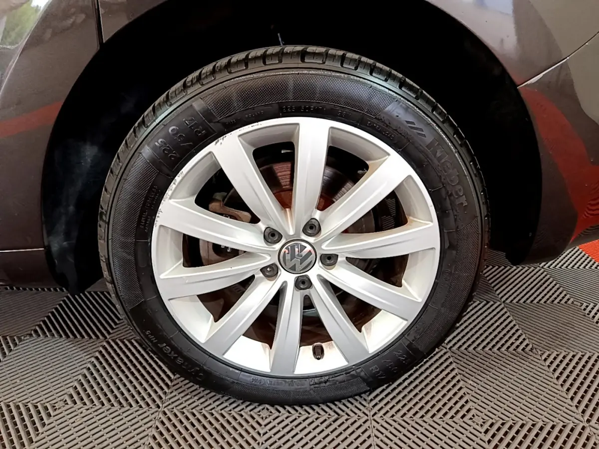 Gros plan sur la roue avant droite marron d'un Volkswagen Sharan 2017 avec jante alliage argentée à 10 branches.