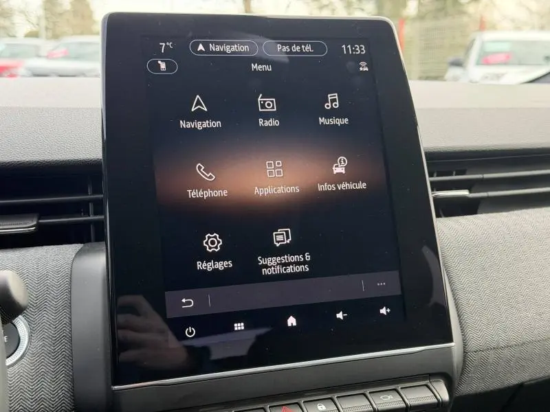 Écran tactile central de la Renault Clio 2025 affichant le menu principal avec navigation, radio et réglages, intérieur gris.