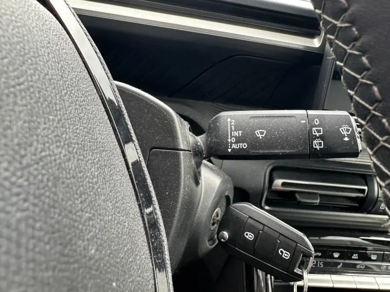 Gros plan sur la commande d’essuie-glace et la clé dans le contacteur d’une Citroën C3 Gris Mercury, intérieur noir.