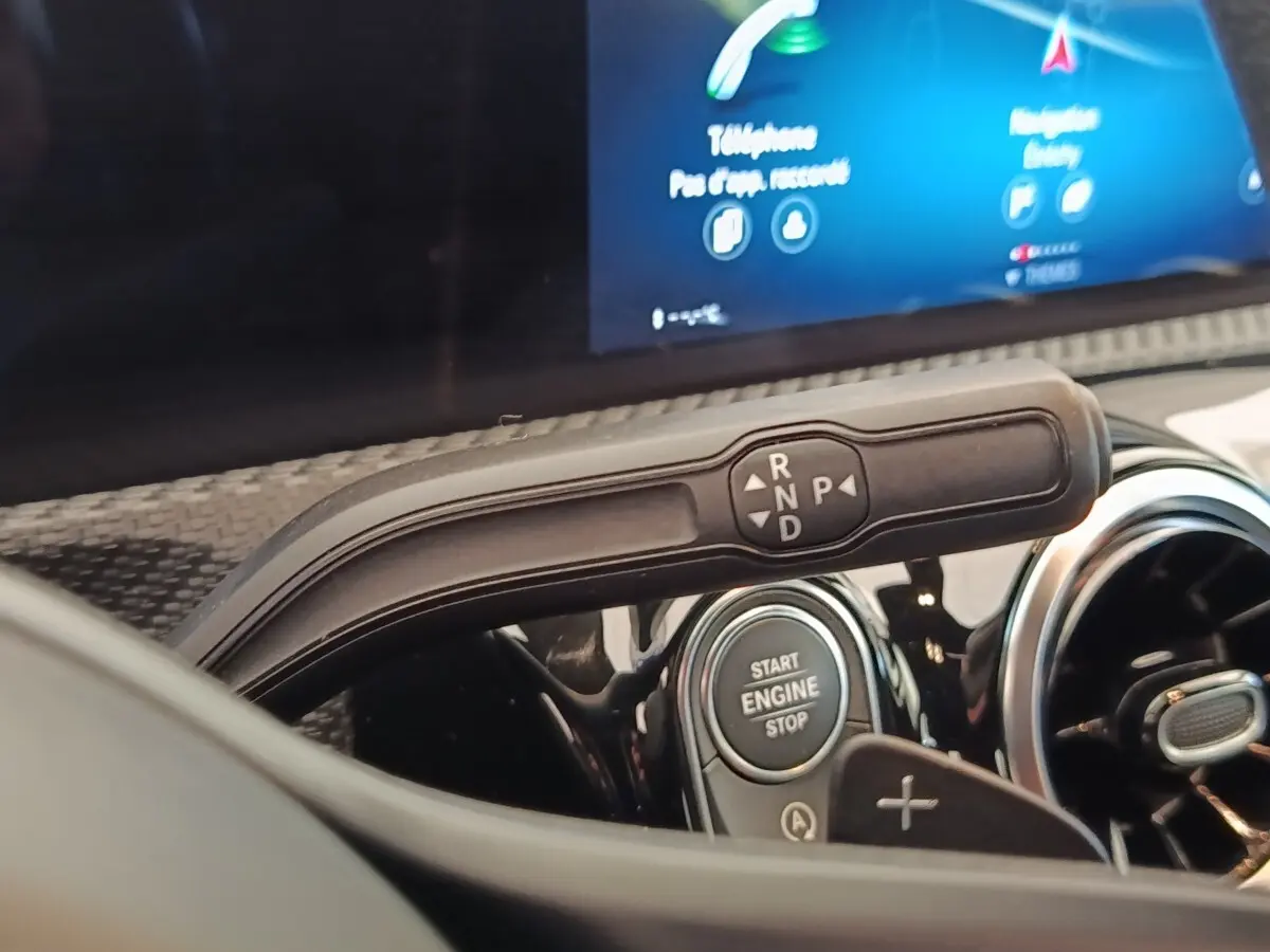 Gros plan sur la commande de boîte automatique et bouton start/stop du tableau de bord d'une Mercedes Classe A gris clair.