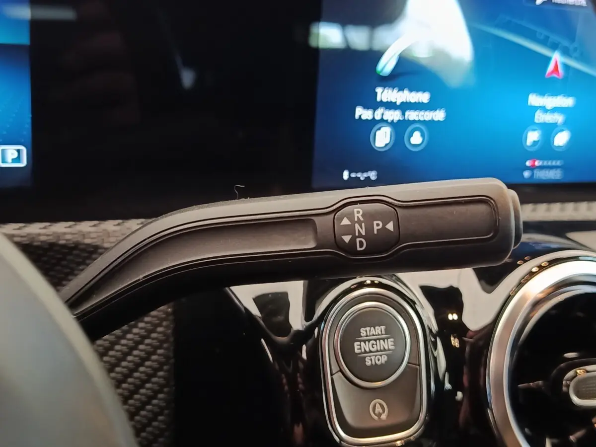 Gros plan intérieur sur la commande de boîte auto et bouton start/stop d’une Mercedes Classe A gris clair.