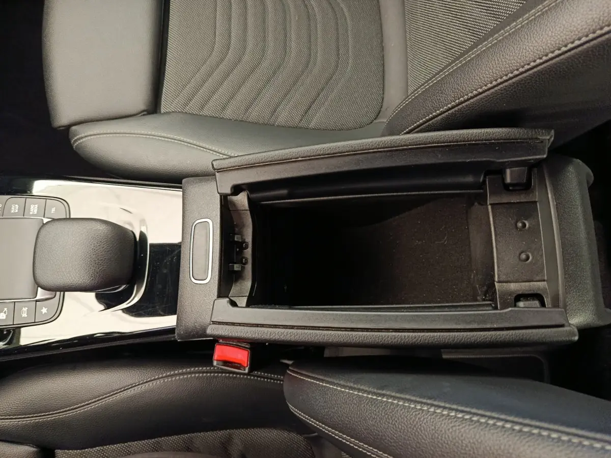 Vue intérieure en plongée du compartiment de rangement central noir et du levier de vitesse d'une Mercedes Classe A gris clair.