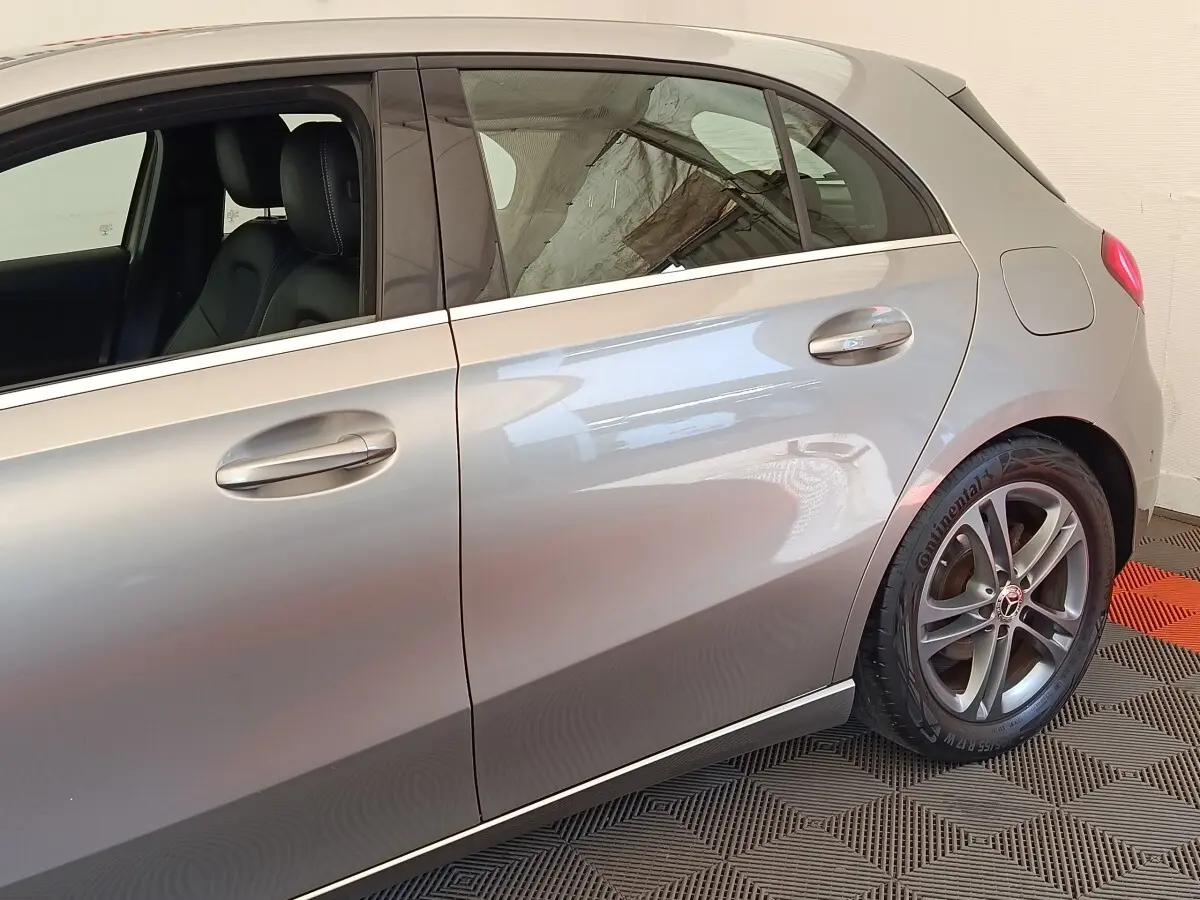 Vue latérale droite d'une Mercedes Classe A A 180 Business Line gris clair, avec jantes alliage et poignées de porte intégrées.