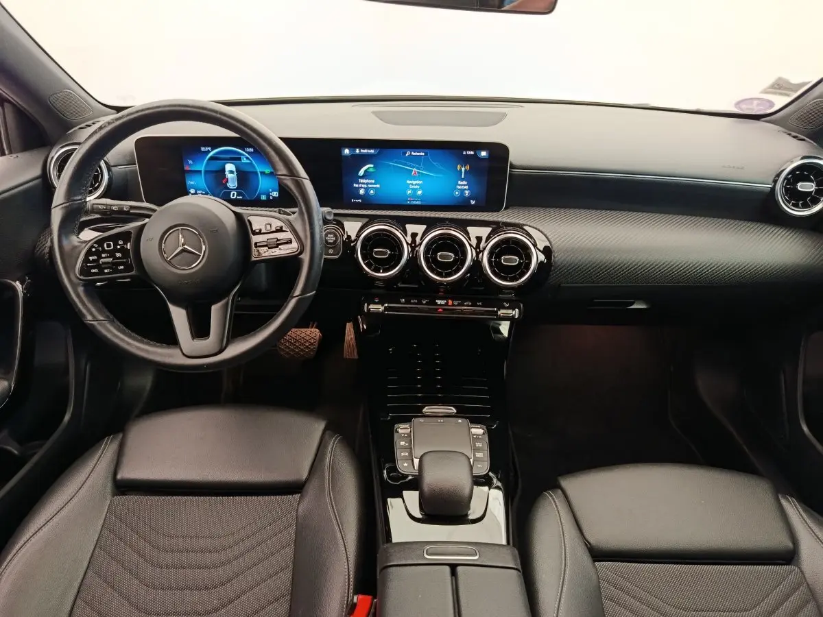 Vue intérieure avant de la Mercedes Classe A 180 Business Line 2020, tableau de bord noir avec écran tactile et volant cuir multifonctions.