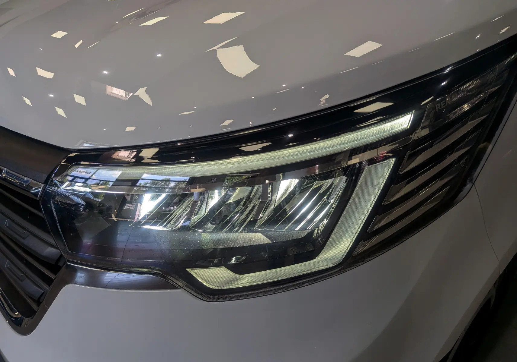 Gros plan sur le phare avant droit du Renault Trafic Fourgon blanc minéral 2024 avec éclairage LED distinctif.