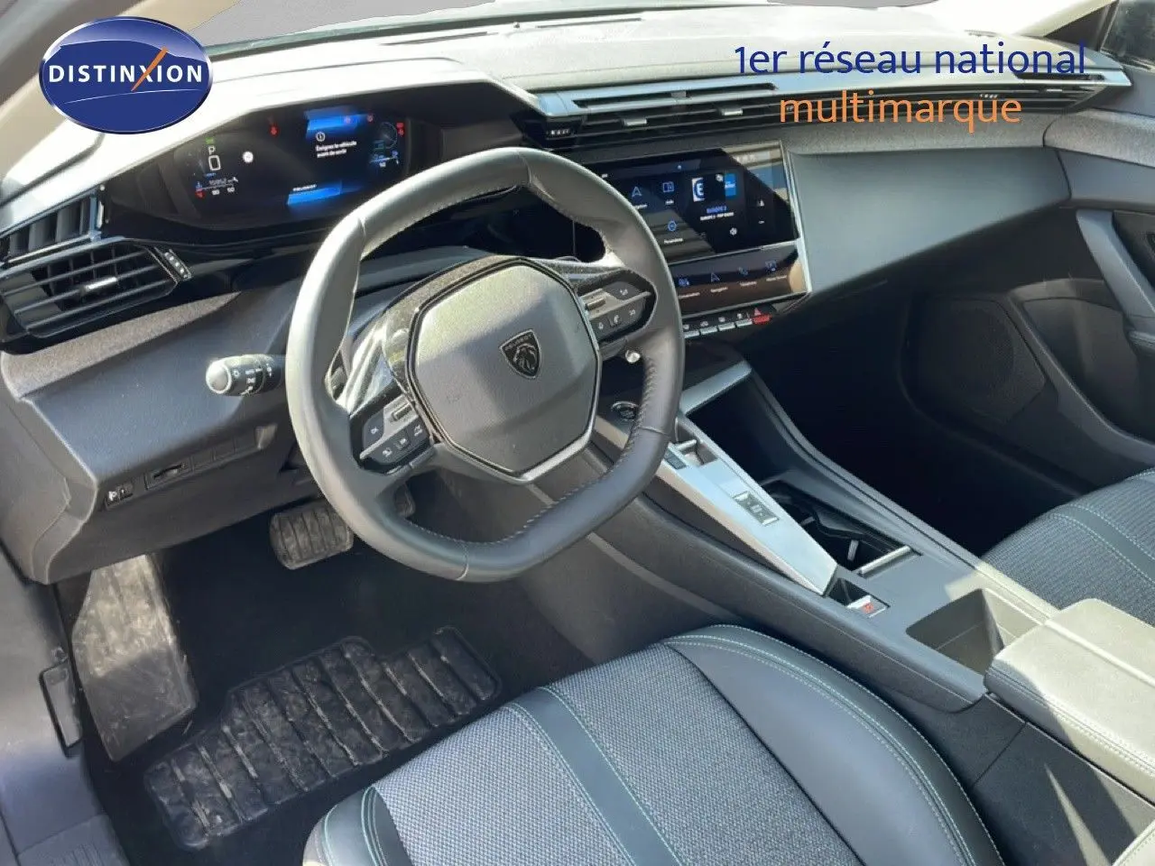 Vue intérieure de face du poste de conduite de la Peugeot 308 SW Hybrid gris avec volant compact et écran tactile central.