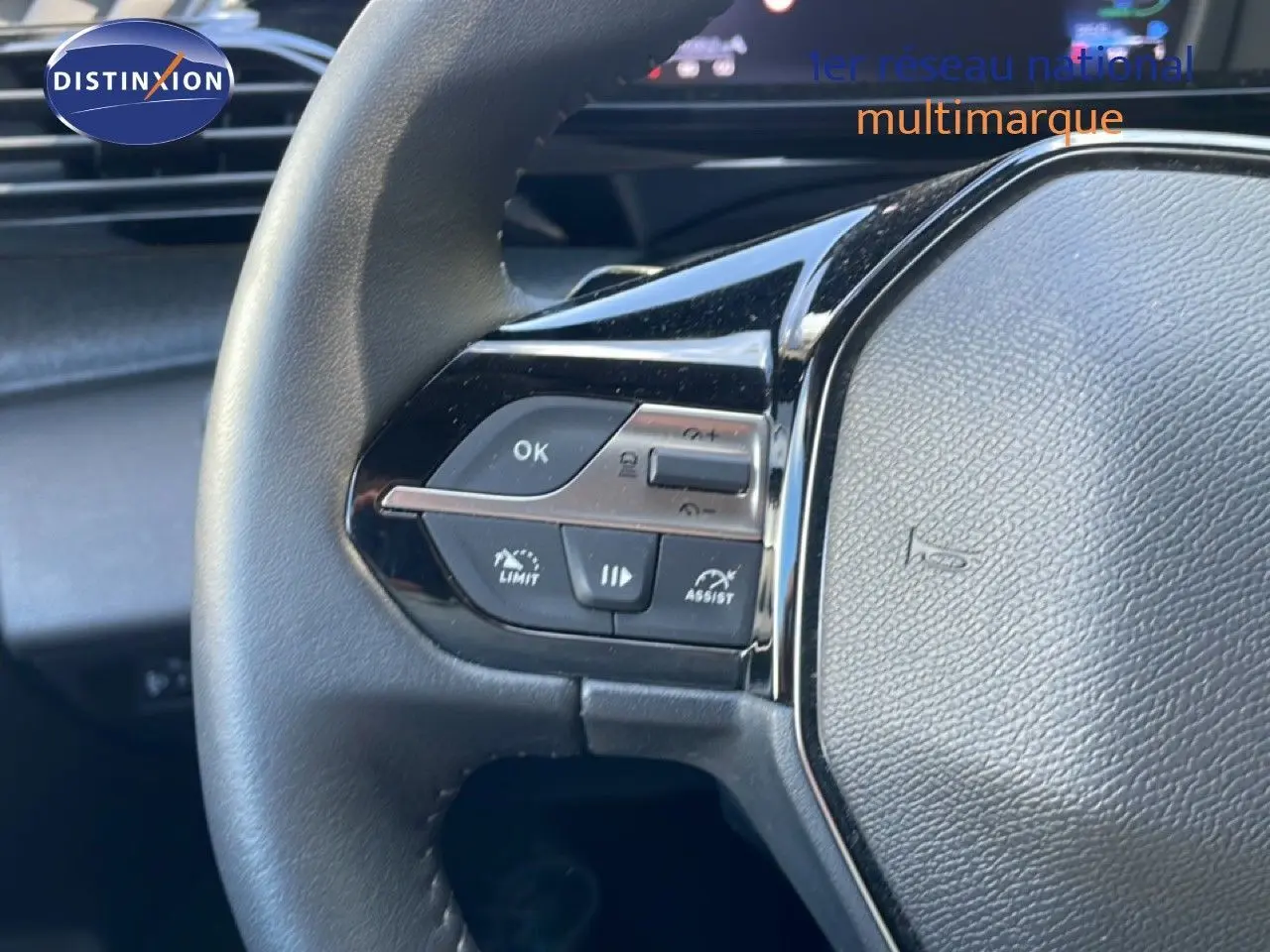 Gros plan sur le volant multifonction noir de la Peugeot 308 SW Hybrid 2025 avec commandes intégrées côté gauche.