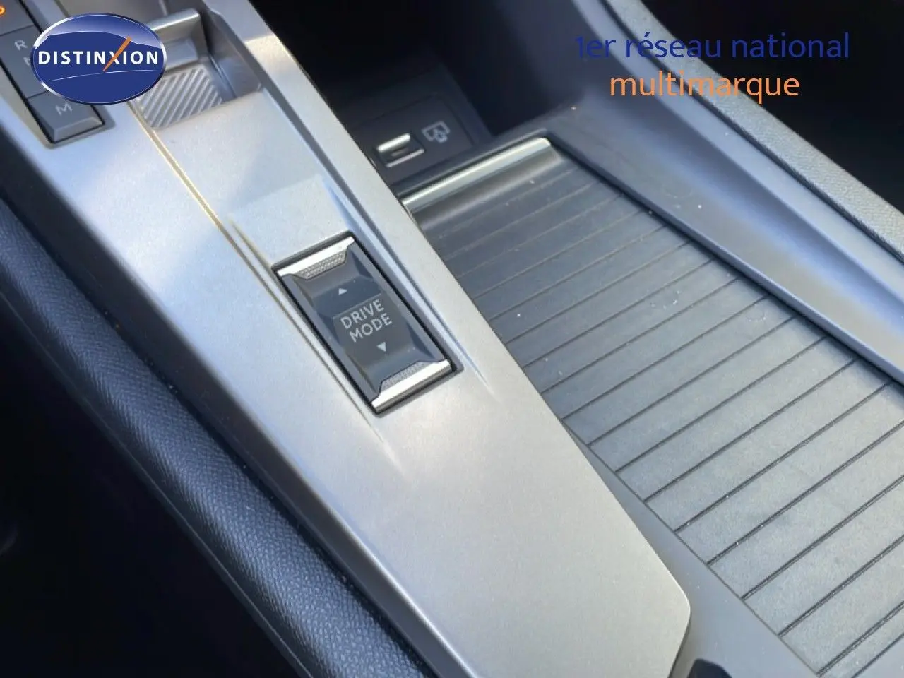 Gros plan sur la console centrale grise du Peugeot 308 SW Hybrid 2025, avec bouton Drive Mode et rangement coulissant.