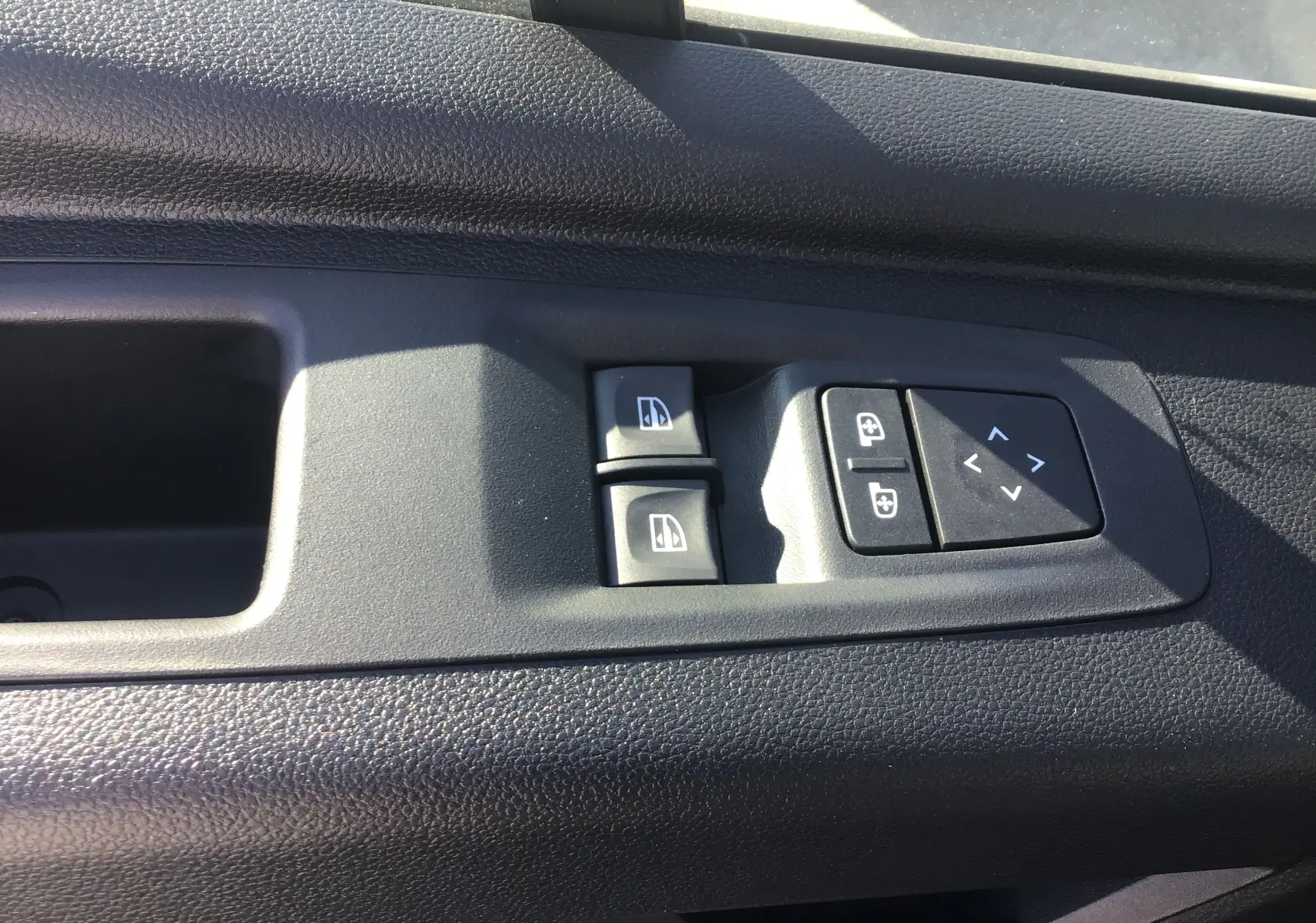 Gros plan sur les commandes de lève-vitres et réglage des rétroviseurs côté conducteur du Renault Master blanc 2025.