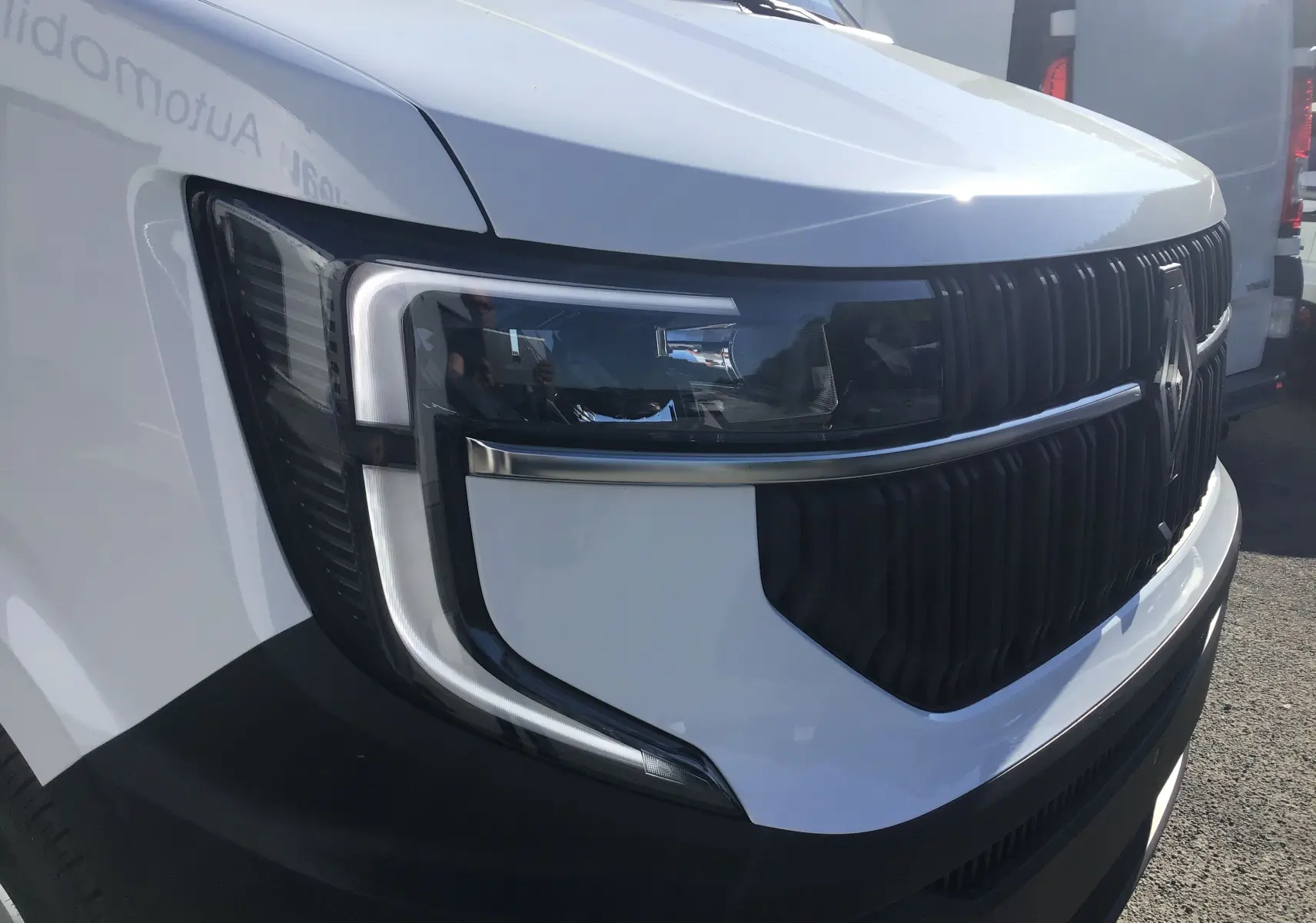 Gros plan sur l'avant gauche du Renault Master blanc 2025, mettant en valeur son phare moderne et sa calandre noire distinctive.