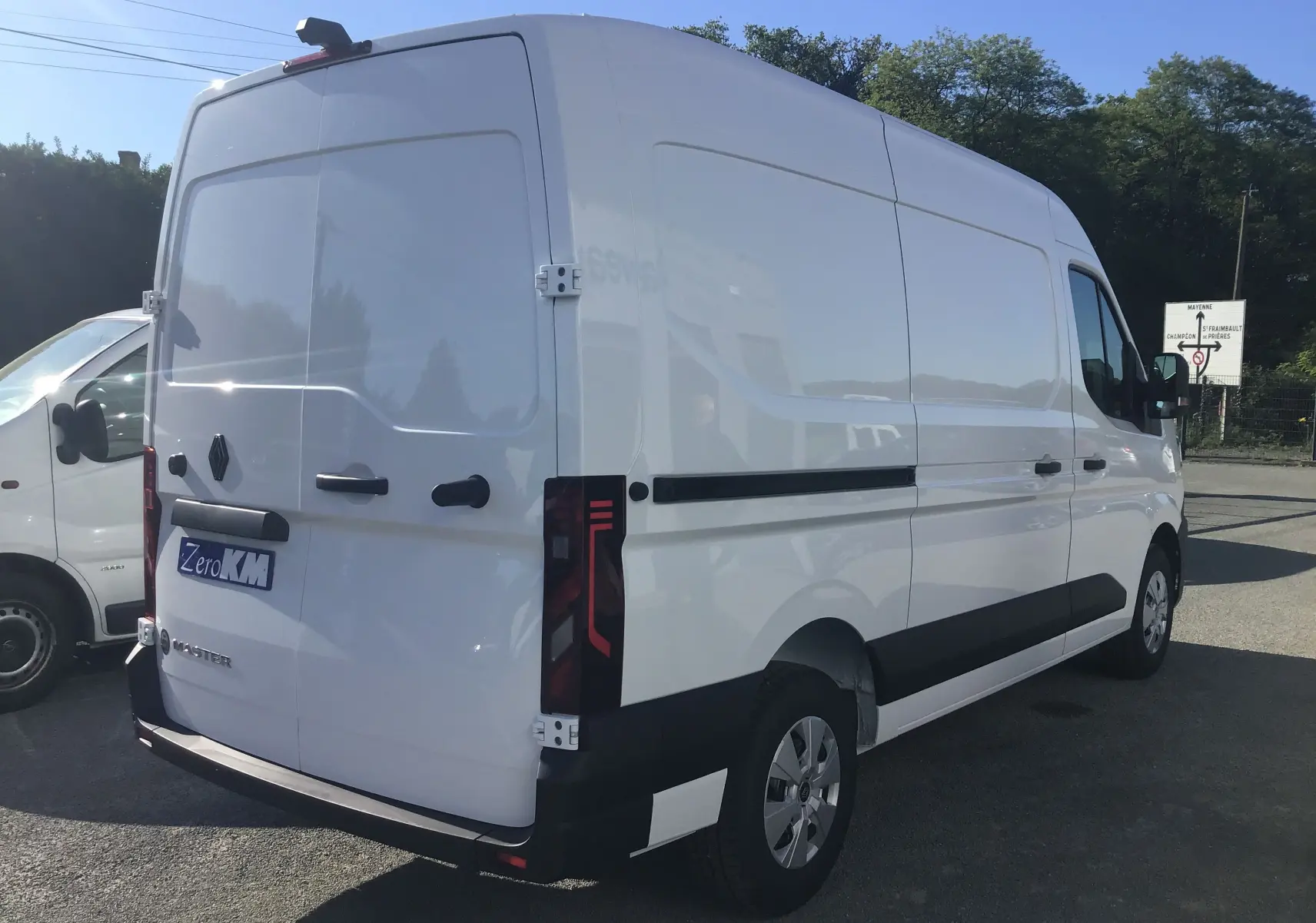 Vue 3/4 arrière droite d'un Renault Master blanc 2025 avec marquage Zero KM et feux arrière modernes.