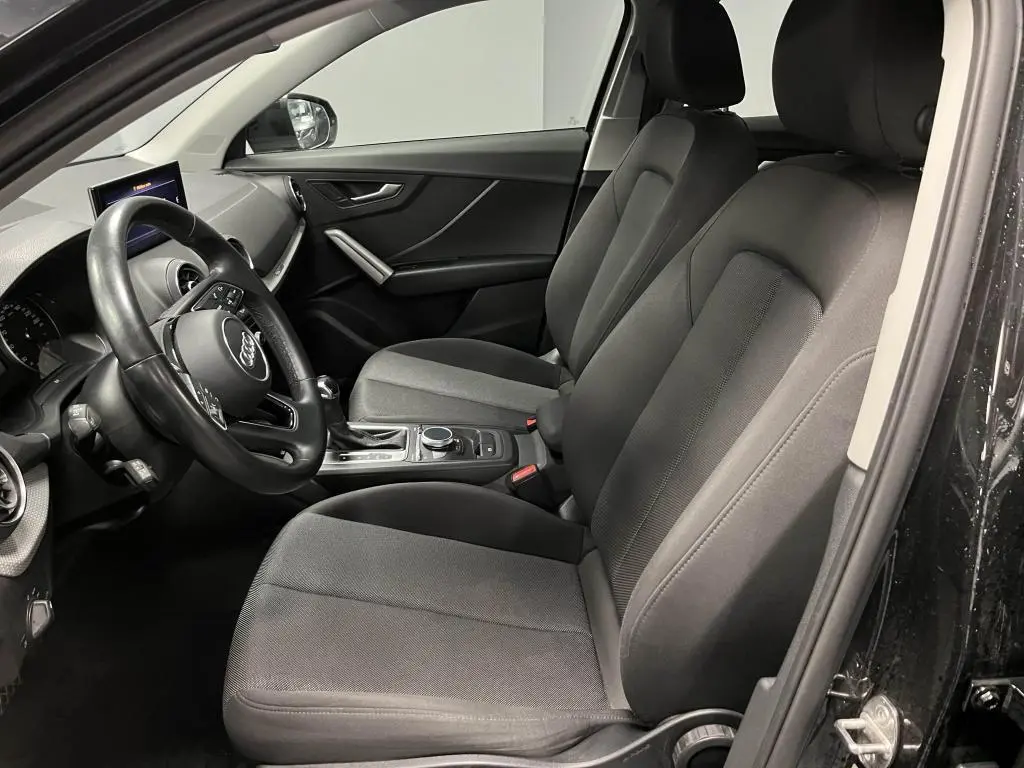 Intérieur avant de l'Audi Q2 noir, vue côté gauche montrant sièges tissu Skript et volant multifonction cuir.