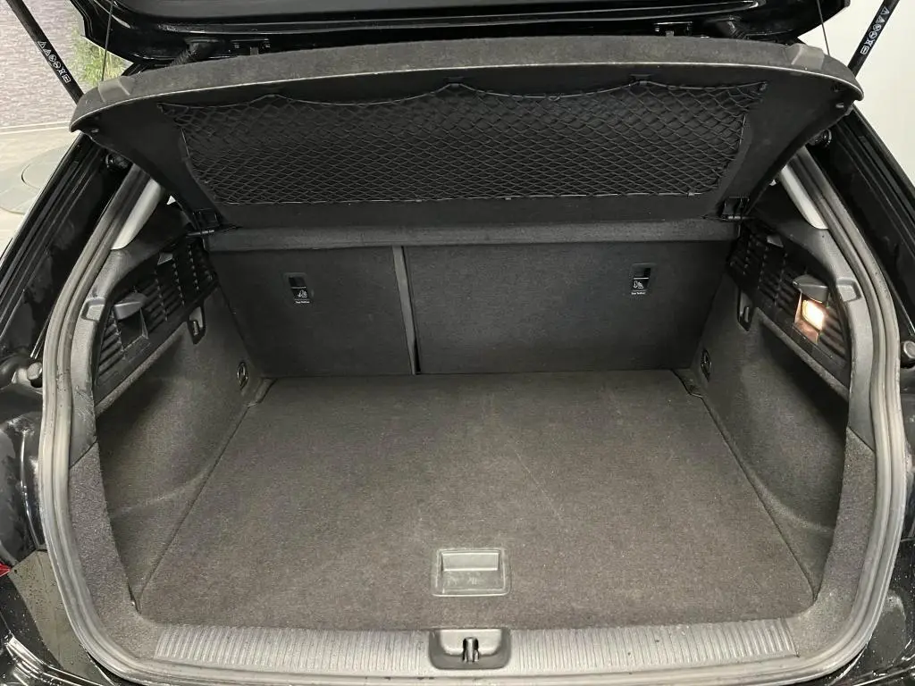 Coffre ouvert de l'Audi Q2 noir 2022, montrant un espace de chargement propre avec filet de rangement sous le hayon.