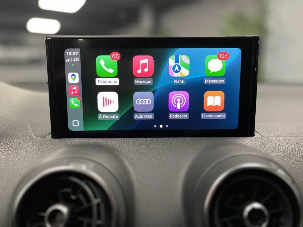 Écran tactile central de l'Audi Q2 2022 affichant l'interface Apple CarPlay avec commandes multimédia visibles.