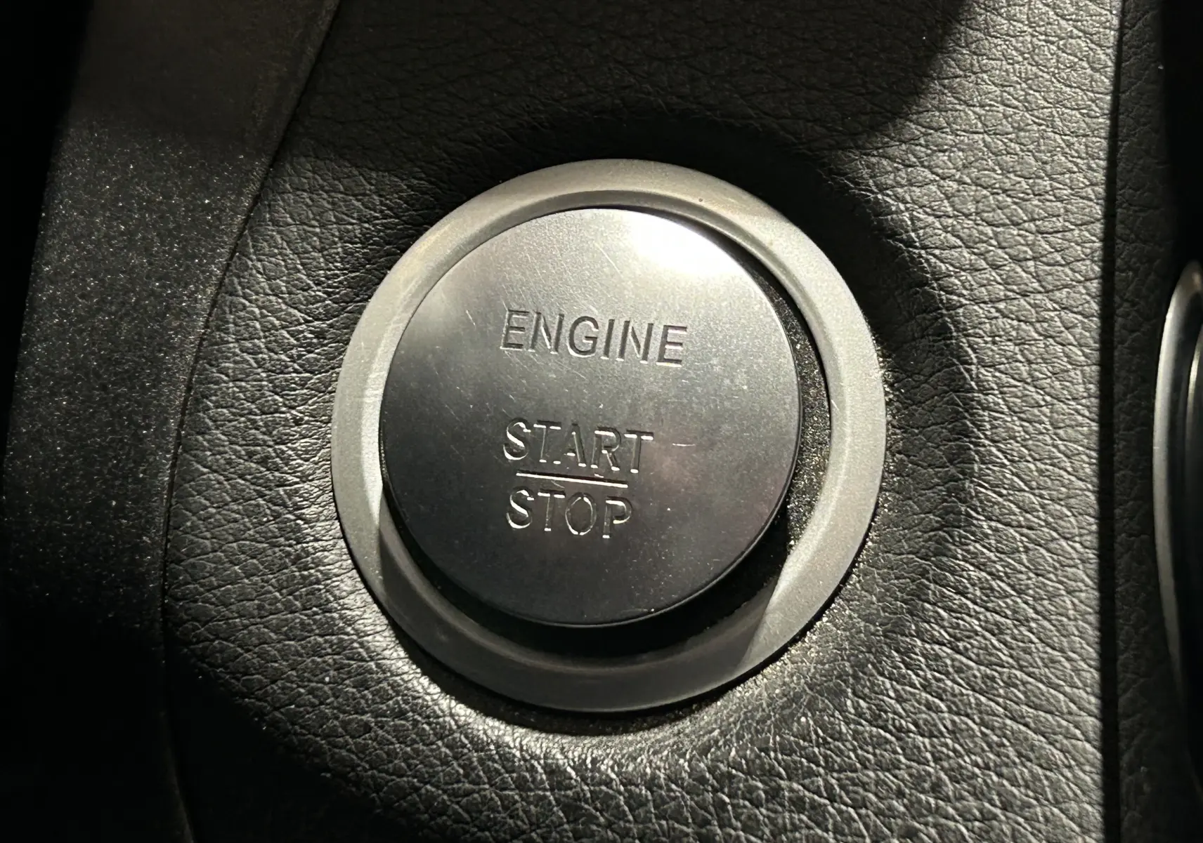 Bouton rond argenté "Engine Start Stop" sur tableau de bord en cuir noir d'une Mercedes Classe C 200d 2018.