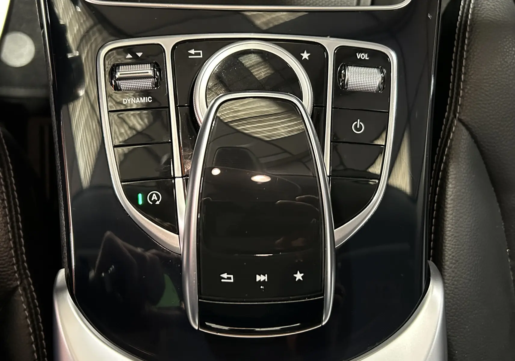 Vue rapprochée de la console centrale noire brillante de la Mercedes Classe C 200d avec commandes tactiles et molette argentée.