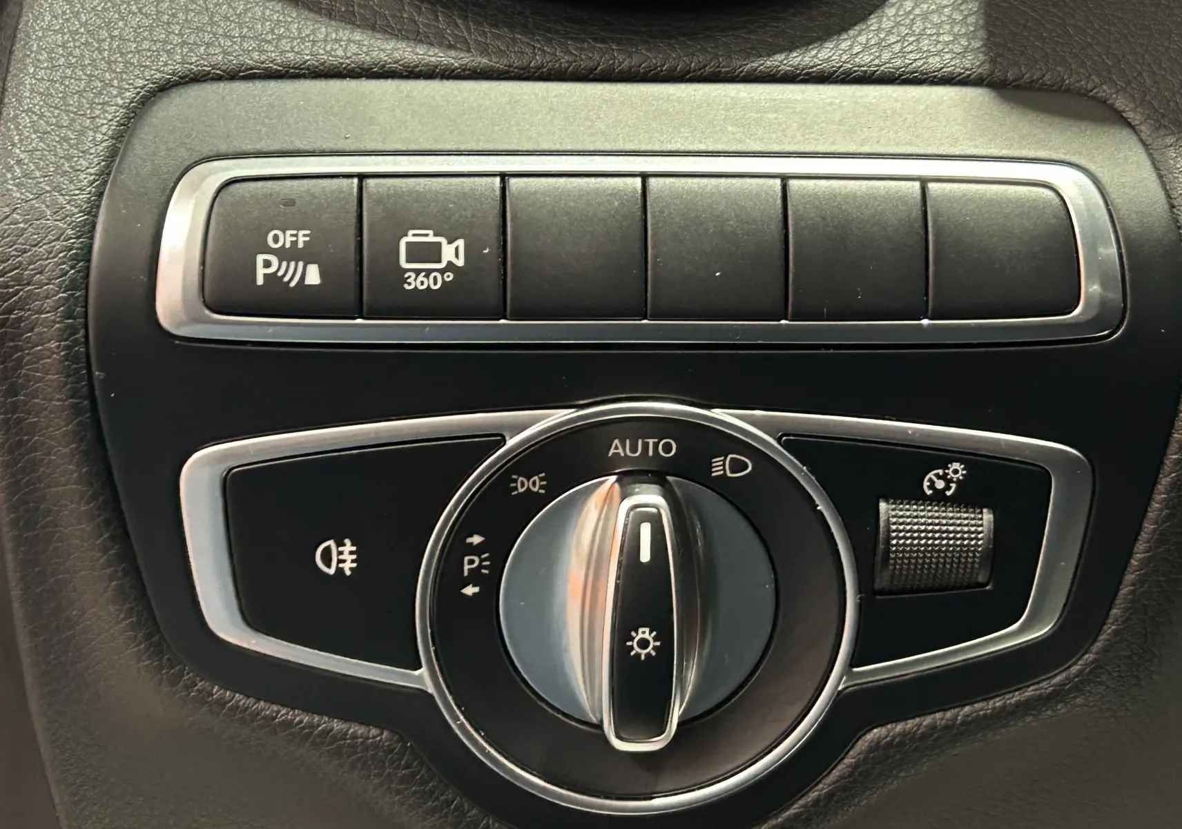 Gros plan sur les commandes d'éclairage et caméra 360° de la Mercedes Classe C 200d bleue, intérieur noir.