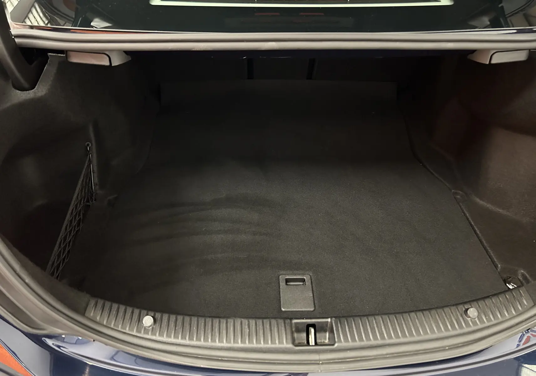 Coffre ouvert vu de dessus d'une Mercedes Classe C 200d bleu, montrant un espace de rangement propre et vide.