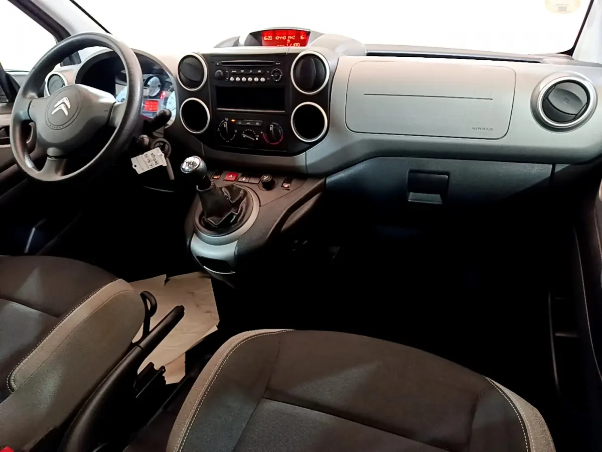 Intérieur du Citroën Berlingo 2016 côté conducteur, tableau de bord gris avec volant noir et levier de vitesses manuel.