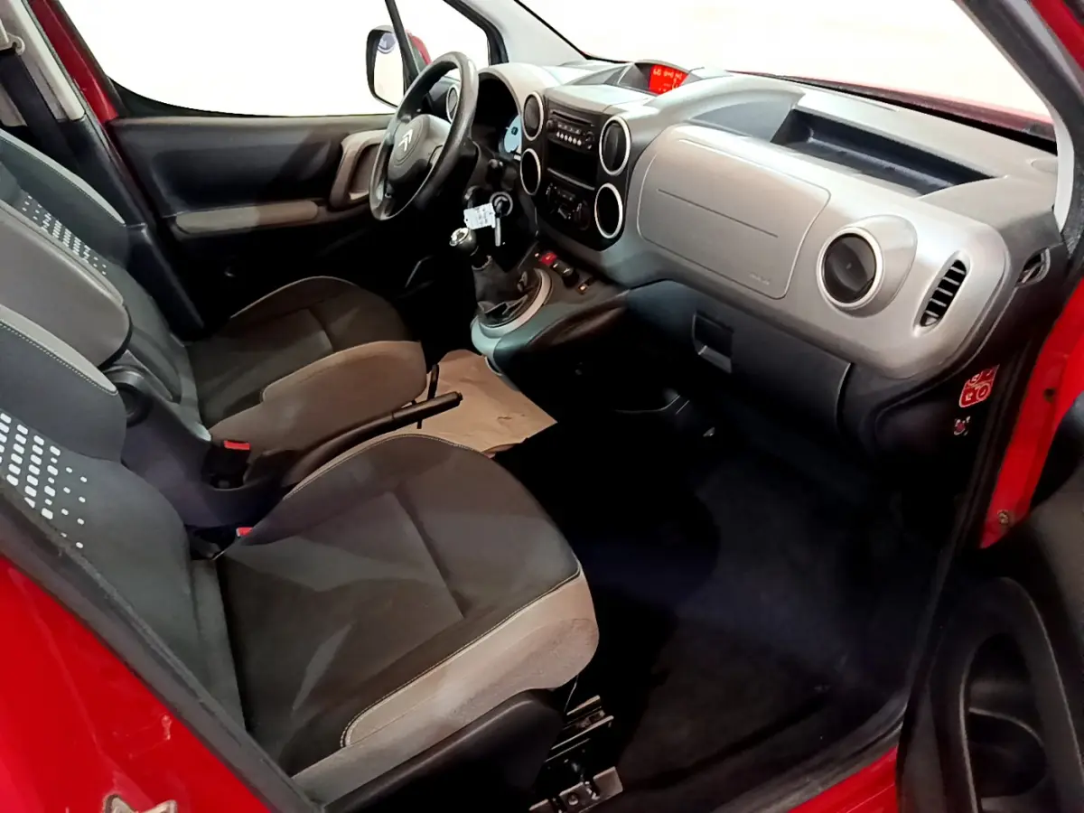 Vue intérieure côté conducteur du Citroën Berlingo rouge 2016, montrant tableau de bord et sièges avant gris.