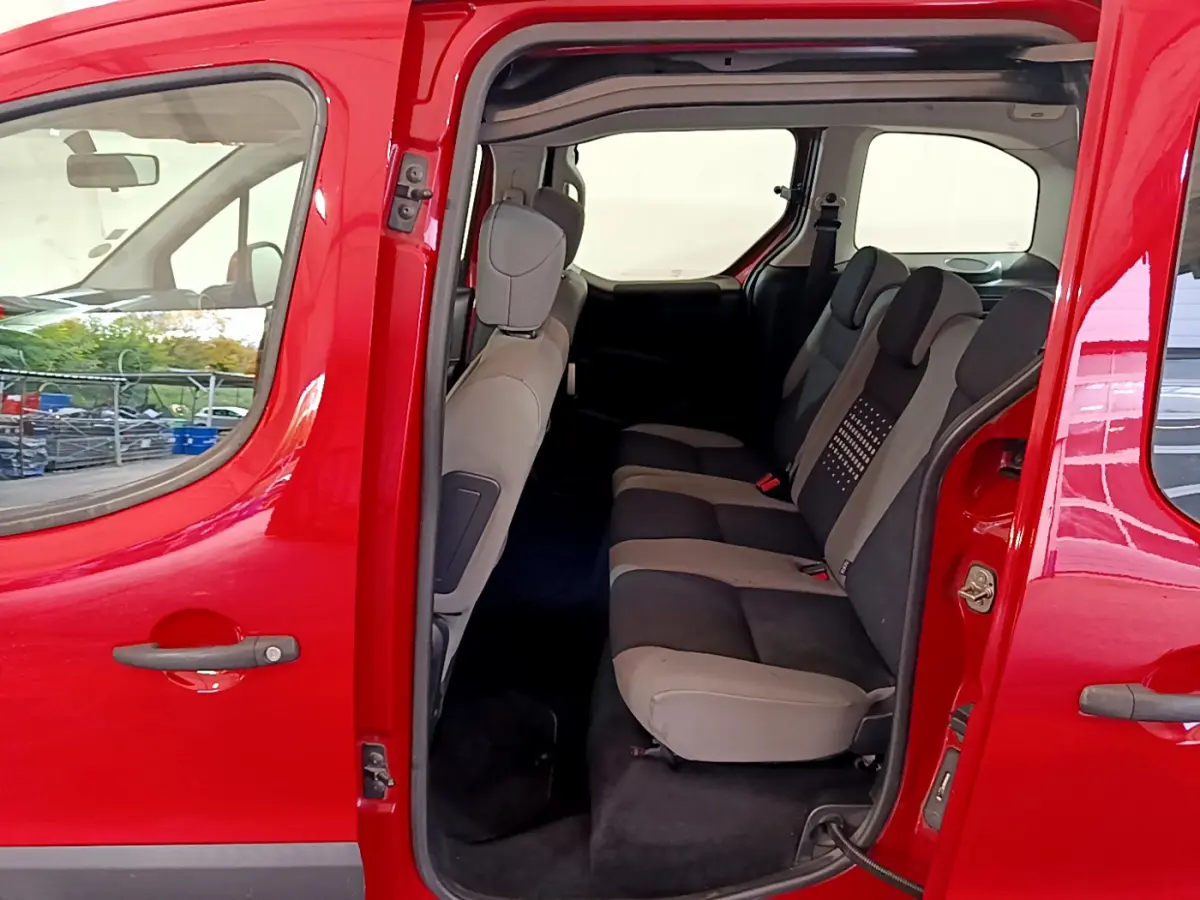 Vue latérale gauche du Citroën Berlingo rouge 2016 montrant les sièges arrière gris et noirs avec porte coulissante ouverte.